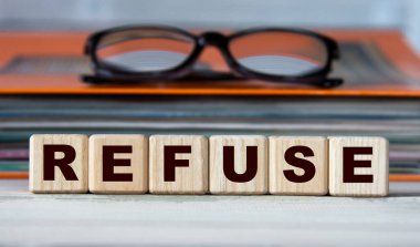 REFUSE - evrak ve gözlüklü bir klasörün arka planındaki tahta küplerle ilgili bir kelime. İş konsepti