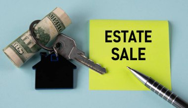 Emlak satışı. Evin anahtarlığı, banknotları ve kalemle birlikte arka planda sarı bir kağıt üzerinde kelimeler. İş konsepti