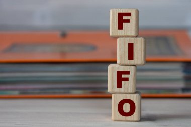 FIFO - acronym on wooden cubes on the background of a folder with documents. Business FIFO first in and out concept.