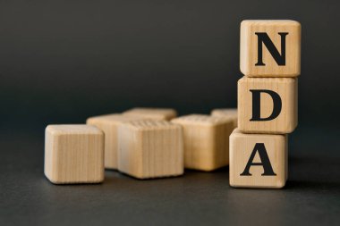 NDA (İfşa Olmama Anlaşması) - koyu arkaplanda tahta küplerin kısaltması. İş konsepti