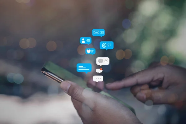 Person using a social media marketing concept on mobile phone with notification icons of like, message, comment and star above smartphone screen.