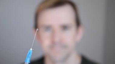 Aşıya karşı insan. Şırıngaya odaklanın. Arka planda sıvı bulunan şırınga. Adamın elini inkar ederek ortaya çıkarması. Vajina kavramı yok. Koronavirüs aşısı önleyici.