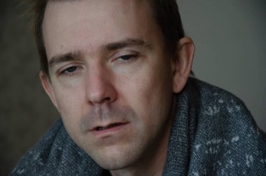 Battaniyenin altındaki hasta beyaz adamın soğuk, kırmızı bir burnu ve hasta bir bakışı var. Hastalık sezonu konsepti.