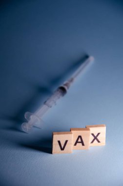 Coronavirus aşısı konsepti. Yazıt Vax bulanık şırınga arka planında duruyor. Kopya alanı ile Harf Vax üzerine seçmeli odaklan. Mavi arkaplanda pankart.