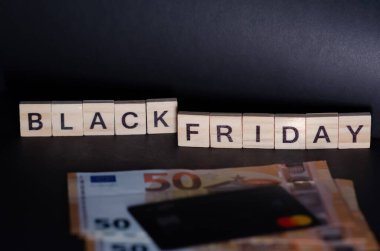 Kara Cuma alışveriş konsepti. Yazıt, siyah arka planda para ve kredi kartının yanında duruyor. Kopya alanı ile Kara Cuma Harflerine Seçici Odaklanma.