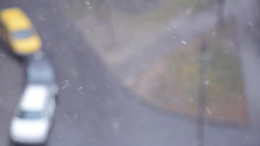 Yoldaki arabaların bulanık arka planlarına kar yağıyor. Şehirde kar yağışı. Kış havası. Kar taneli arkaplan.