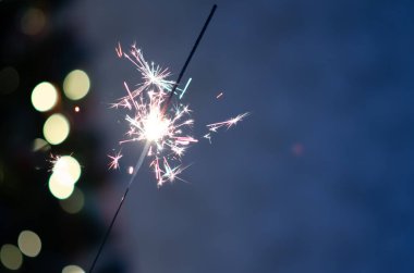 Fotokopi alanı olan bir Noel afişi. Bokeh ışıklı arka planda yanan maytap. Yeni yıl ışıklarının arka planında maytap kıvılcımları var. Noel arifesi.