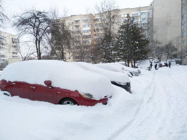 Arabalar karla kaplıdır. Şehirde kış havası var. Kar fırtınası otoparkı ve yüksek binalar arasındaki yolu kapladı. Kar çökmesi.