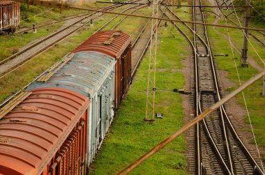 Old freight cars of the train stand on rails. The train stopped at the station in the village. Rusty iron cars and green grass. Railway background with copy space.
