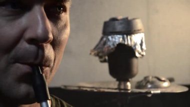 Beyaz adam nargile içiyor. Shisha piposu içen ve nefes veren genç bir adamın portresi. Rahatlama konsepti.