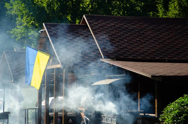 乌克兰卢茨克 2021年8月19日 乌克兰国旗飘扬在公园娱乐区的房顶上 咖啡店附近的烤面包和烤面包一起吸烟 乌克兰企业的概念 — 图库照片