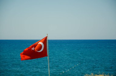 Mavi gökyüzüne ve denize karşı bayrak direğinde dalgalanan Türk bayrağı. Türkiye 'nin ulusal kırmızı ve beyaz bayrağı kentin üzerine asıldı.