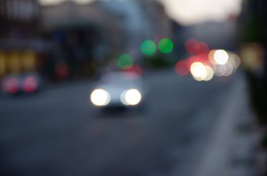 Akşamları şehir trafiğinin yoğunluğu azalıyor. Şehir caddesinde trafik sıkışıklığının odak ışıklarından. Şehir geçmişi bulanık. Akşam trafiğinin bokeh dairelerini hareket ettiriyor.