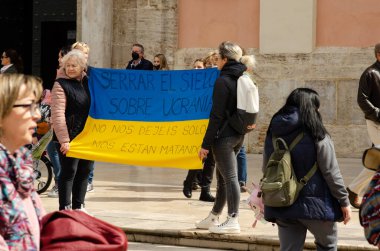 27 Mart 2022 Valencia, İspanya. İspanyollar ve Ukraynalılar Ukrayna 'daki savaşa karşı. Kadınlar Ukrayna bayrağını gökyüzünün kapatılmasıyla ilgili yazıyla tutuyorlar. Cerrar el cielo ayık Ucrania. Hayır dejes solo, nos estan matando.
