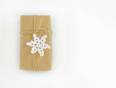 Noel ve Yeni Yıl düz yatış geçmişi. Kraft kağıdına sarılı jute kablosuyla hediye kutusu. Tığ işi bir kar tanesiyle süslenmiş. Metnin için yer