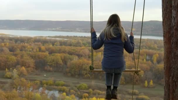 The girl rides on a swing at a high altitude. Swing on the mountain in nature. Spring break on the hill — Stock Video