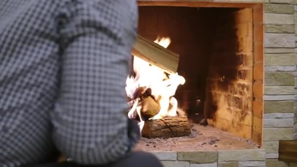 En man kastar tjockt ved i eldstaden — Stockvideo