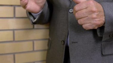 Takım elbiseli yetişkin bir adam elleriyle hareket eder. İnsan biriyle iletişim kurar.