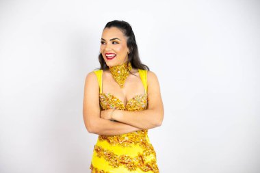 Karnaval kostümü giymiş genç güzel bir kadın izole edilmiş beyaz arka planda yan tarafa bakıyor, rahat bir poz veriyor ve kendine güvenen bir gülümseme takınıyor..