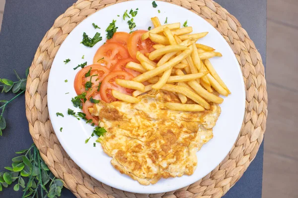 french omelette dish with tomato and chips