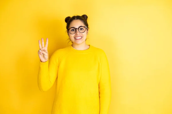 年轻而漂亮的女人穿着休闲装 披着孤立的黄色背景 带着自信和快乐的笑容 用手指头指着三号 — 图库照片