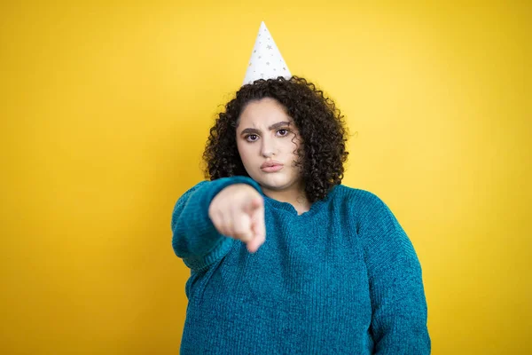 Jonge Mooie Vrouw Met Een Verjaardagshoed Geïsoleerde Gele Achtergrond Wijzend — Stockfoto