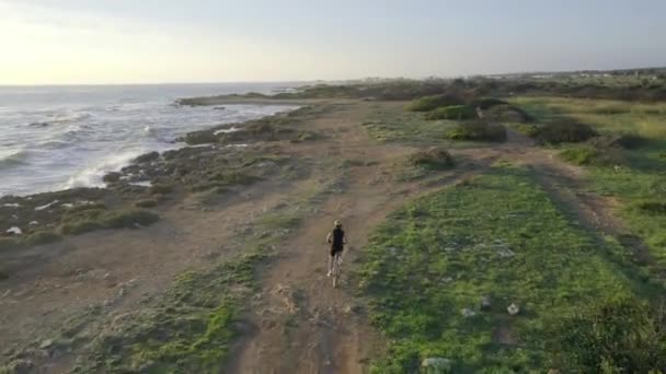 Mujer ciclismo en la playa, aérea al atardecer — Vídeo de stock