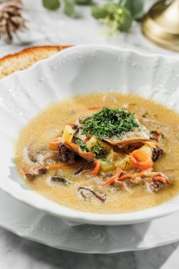 Hafif mermer arka plandaki beyaz tabakta et ve sebzeli lezzetli çorba. Sağlıklı deniz ürünleri, sert ışık, restoran dekorasyonu, yakın çekim.