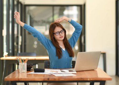 Mavi gömlekli Asyalı kadın rahatlamak için kollarını açıyor. Ofiste çalışırken, ofis sendromu, iş fikri, ofis ekipmanları....