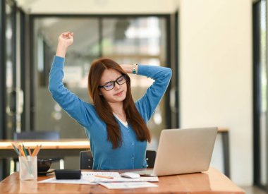 Mavi gömlekli Asyalı kadın rahatlamak için kollarını açıyor. Ofiste çalışırken, ofis sendromu, iş fikri, ofis ekipmanları....