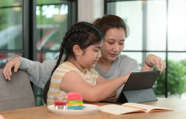 Asian girl studying privately with tutor at home, siblings teaching homework, online learning.