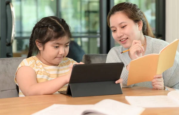 Asian girl studying privately with tutor at home, siblings teaching homework, online learning.