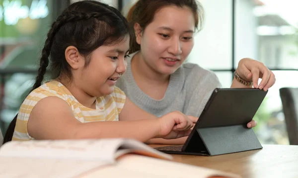 Asian girl studying privately with tutor at home, siblings teaching homework, online learning.