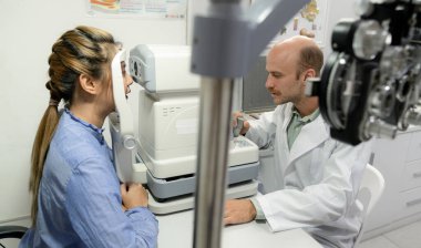 Gözleri beyaz formda bir optometrist tarafından incelenen genç kadın, optometrist, üst yarısının yakın plan fotoğrafı..