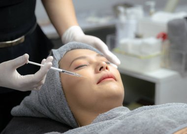Güzellik uzmanı, genç kadınların yüzlerini, güzellik kliniklerini, temiz yüz için mezoterapiyi beslemek için vitamin enjekte eder ve özümser..