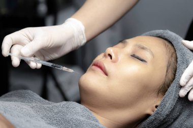 Güzellik uzmanı, genç kadınların yüzlerini, güzellik kliniklerini, temiz yüz için mezoterapiyi beslemek için vitamin enjekte eder ve özümser..