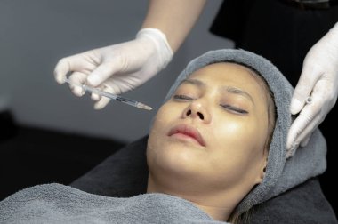 Güzellik uzmanı, genç kadınların yüzlerini, güzellik kliniklerini, temiz yüz için mezoterapiyi beslemek için vitamin enjekte eder ve özümser..