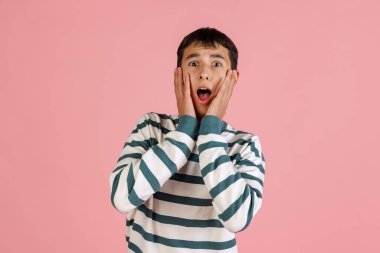 Pembe stüdyo arka planında izole edilmiş günlük giysiler içindeki genç adam, öğrenci ya da çocuk portresi. İnsan duyguları kavramı.