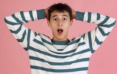 Pembe stüdyo arka planında izole edilmiş günlük giysiler içindeki genç adam, öğrenci ya da çocuk portresi. İnsan duyguları kavramı.