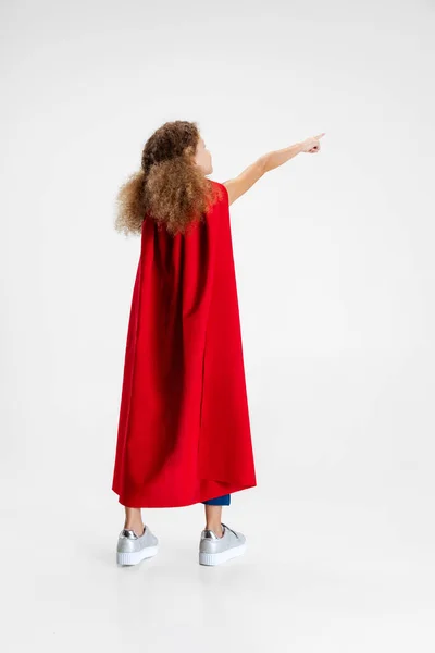Visão traseira da menina, criança de pé de costas para a câmera vestindo capa vermelha isolada no fundo do estúdio cinza com copyspace para anúncio — Fotografia de Stock