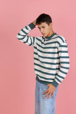 Pembe stüdyo arka planında izole edilmiş günlük giysiler içindeki genç adam, öğrenci ya da çocuk portresi. İnsan duyguları kavramı.