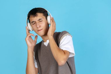 Müzisyen. Mavi stüdyo arka planında izole edilmiş günlük giysiler içindeki genç adam, öğrenci ya da çocuk portresi. İnsan duyguları kavramı.