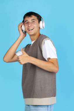 Müzisyen. Mavi stüdyo arka planında izole edilmiş günlük giysiler içindeki genç adam, öğrenci ya da çocuk portresi. İnsan duyguları kavramı.