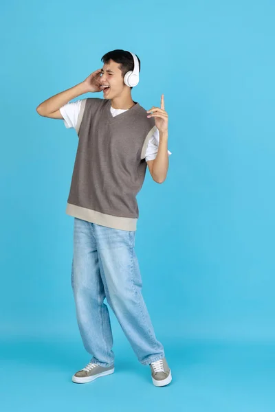 Musiker. Porträtt av ung man, student eller pojke i avslappnade kläder isolerade på blå studio backgroud. Begreppet mänskliga känslor. — Stockfoto