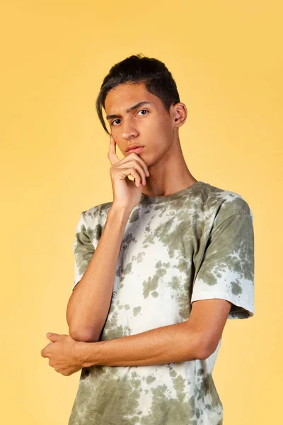 평범 한 옷을 입은 학생 이 노란 스튜디오 뒤에서 고립된 모습의 젊고 잘생긴 소년의 초상화. 인간의 감정 개념. — 스톡 사진
