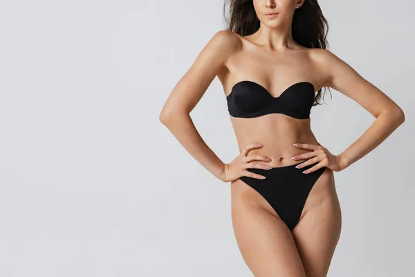 Imagem recortada de corpo feminino esportivo em lingerie preta posando isolado no fundo do estúdio cinza claro. Conceito de beleza natural. — Fotografia de Stock