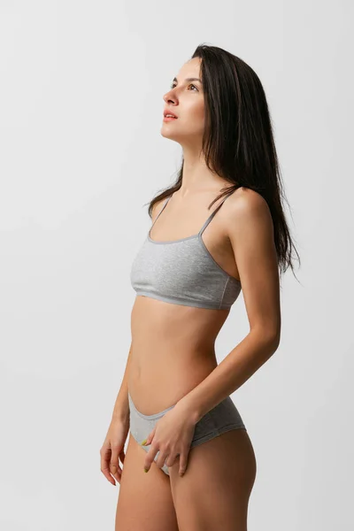 Portrait of young beautiful slim woman in grey lingerie,bra and panties posing isolated over gray studio background. Natural beauty concept. — Stock Photo, Image