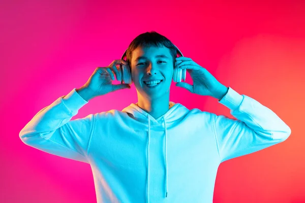 Portrait of young man, student or boy in casual clothes smiling isolated on magenta studio backgroud in neon. Human emotions concept. — Stock Photo, Image