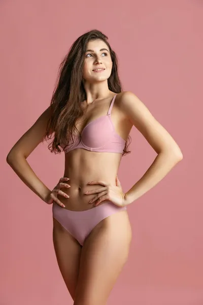 Retrato de jovem bela mulher magra em lingerie posando isolado sobre fundo de estúdio rosa. Conceito de beleza natural. — Fotografia de Stock