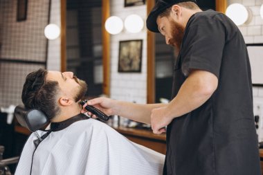 Profesyonel berber, kırpıcı, berber dükkanındaki düzenli müşterinin tıraş sakalı. Güzellik, bencillik, tarz, moda ve erkek kozmetik konsepti.